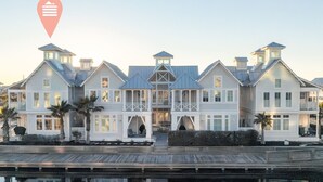 Un'ampia proprietà fronte mare, a più piani, con un design simmetrico, caratterizzata da numerosi balconi e un portico coperto.