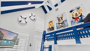 Quarto com cama beliche, decoração temática náutica e uma grande janela vista para uma piscina.