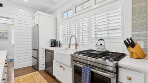 Uma cozinha moderna com armários brancos, fogão de aço inoxidável e cafeteira.