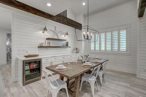 A modern kitchen with white paneling, wooden beams, and a central island with seating. - Seashell Sanctuary 242 GR (Port Aransas)