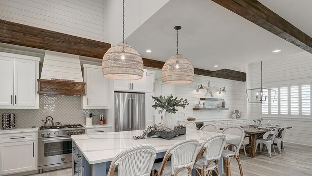 A spacious kitchen with white cabinetry, a large island, and wicker chairs. - Seashell Sanctuary 242 GR (Port Aransas)