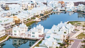 A coastal residential area with houses along a waterway, featuring a dock and a small boat. - 5 O'clock Four Shore 205 Fiv-f (Port Aransas)