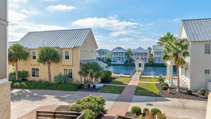 A residential area with multiple houses, a pathway, and a body of water in the background. - Lucky Ole Sun TC 3205 (Port Aransas)