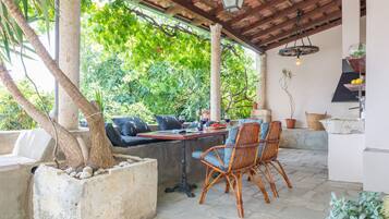 An outdoor patio with a table, chairs, and a potted plant.