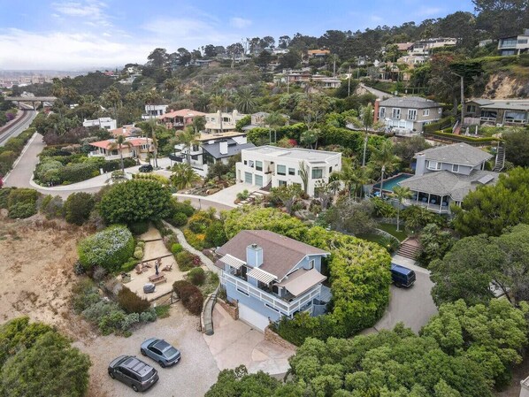 A residential area with houses, a swimming pool, and a driveway with cars.