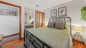 A bedroom with a bed, a mirror, a bedside table, and a lamp. - Darling Beach Cottage, Ocean Views, central (Del Mar)