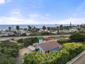 A coastal residential area with houses, a beach, and a clear sky.