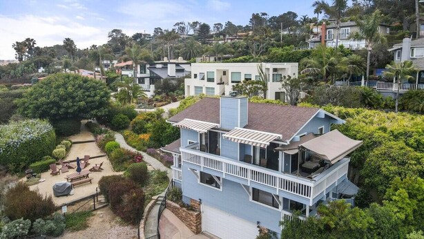 A two-story house with a balcony, surrounded by lush greenery and a clear sky. - Darling Beach Cottage, Ocean Views, central (Del Mar)