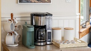 A kitchen counter with a coffee maker, a water dispenser, and a tray of tea bags. - Darling Beach Cottage, Ocean Views, central (Del Mar)