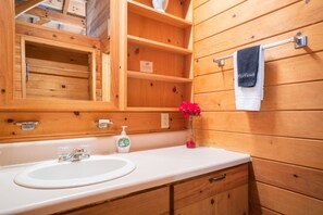A wooden bathroom with a white sink, a mirror, and a towel rack.