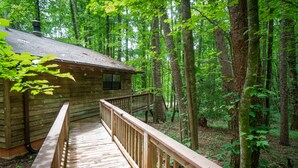 A wooden cabin with a deck and a staircase leading to the entrance.