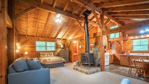 A log cabin interior with a cozy living area, a fireplace, a kitchen, and a dining space.