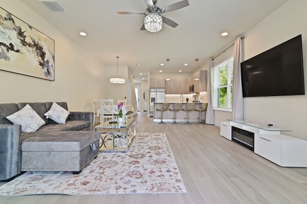 A modern living room with a grey sectional sofa, a glass coffee table, and a floral rug.