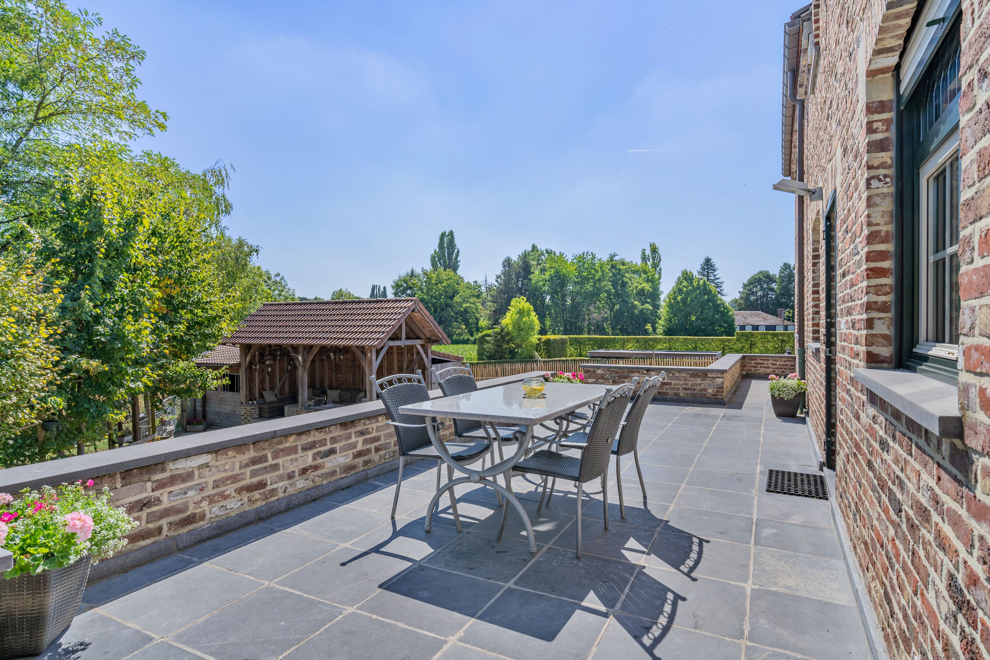 A patio with a table and chairs, surrounded by brick walls and potted plants.