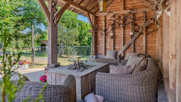 A rustic wooden cabin with a covered patio, wicker furniture, and antler decorations.