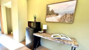 A room with a wooden floor, a desk with a book, a microwave, and a small plant on a cabinet. - #2 Alder Queen Room - Fireplace in Olympic Nat'l Pk (Port Angeles)
