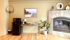 A living room with a stone fireplace, a small table with a plant, and a framed picture on the wall. - #2 Alder Queen Room - Fireplace in Olympic Nat'l Pk (Port Angeles)