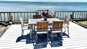 Terraza de madera con mesa y sillas con vista al agua.