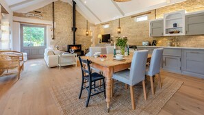Una cocina amplia con pared de piedra, electrodomésticos modernos y un comedor con mesa y sillas de madera.
