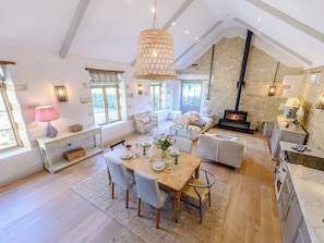 A spacious loft with a high ceiling, stone walls, a fireplace, and a dining area with a wooden table and chairs.