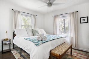 Un dormitorio con cama, mesita de noche y una banca.
