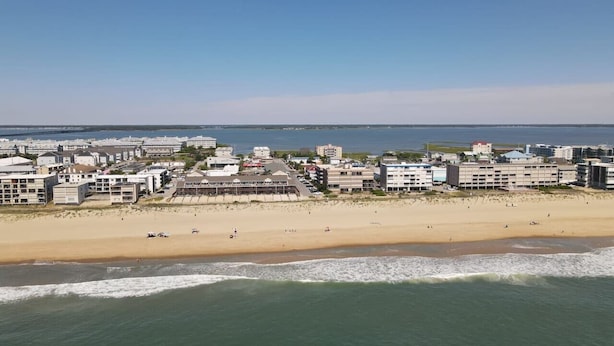 A coastal cityscape with a wide sandy beach, a marina, and a variety of buildings including hotels and residential structures.