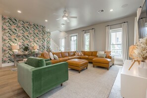 A spacious living room with a sectional sofa, a green armchair, and a decorative lamp.