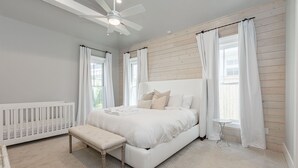 Ein Schlafzimmer mit einem weißen Bett, einer Bank, einem kleinen Tisch und einem Deckenventilator.