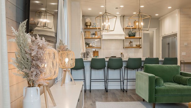 Eine moderne Küche mit Kochinsel, Barhocker und einem grünen Sofa.
