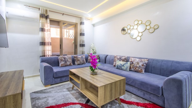 Een moderne woonkamer met een bank, salontafel en decoratieve spiegels.