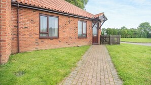 Ein Ziegelhaus mit Ziegeldach, einem gepflasterten Auffahrt und einem Holzzaun.