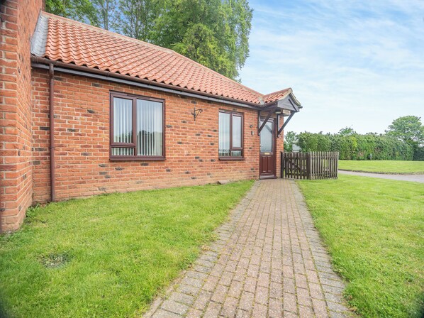 A brick house with a tiled roof, a paved driveway, and a wooden fence.
