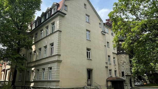 A multi-story building with a beige facade, a stone entrance, and a small garden area. - Modern holiday flat with comfortable furnishings, quiet and centrally located (Weimar)