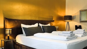 A neatly made bed with white linens and multiple pillows, a bedside lamp, and a folded towel on the side. - Modern holiday flat with comfortable furnishings, quiet and centrally located (Weimar)