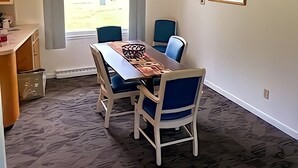 En matplats med ett bord och stolar, ett fönster med utsikt och en inramad tavla på väggen.