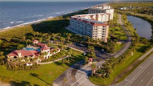 Luftaufnahme eines Resorts mit einem großen Gebäude, einem Schwimmbad und einem Strand.