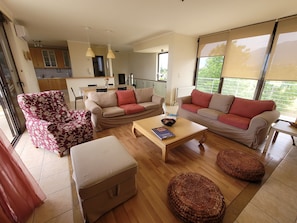 A living room with a sofa, armchair, ottoman, coffee table, and woven pouf.