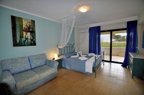 A bedroom with a bed, a sofa, a nightstand, a painting, and a view through a glass door.