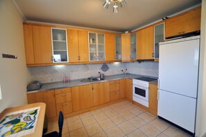Uma cozinha com armários de madeira, geladeira branca, fogão e painel de azulejos.