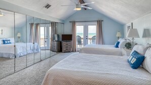 Un dormitorio con dos camas, ventilador de techo, televisor y un espejo grande.