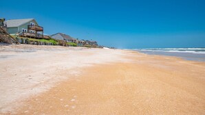 Una playa con una fila de casas y un cielo azul despejado.