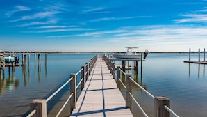 A wooden pier extending into calm water with a boat docked at the end. - Waterfront Paradise (St. Augustine)