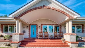 A two-story house with a covered porch, a blue door, and a number '120' on the wall. - Waterfront Paradise (St. Augustine)