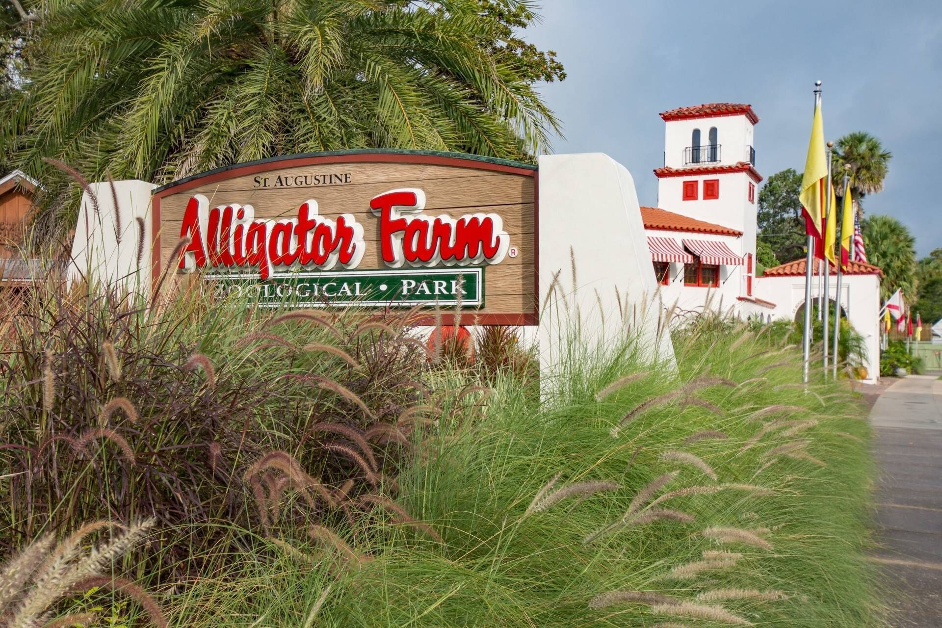Un cartel para Alligator Farm, un parque zoológico, con un edificio al fondo.