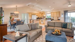 A spacious living area with a sofa, ottoman, and coffee table, a dining area with chairs and a table, and a kitchen with cabinets and appliances. - Sunshine Daydream (St. Augustine)
