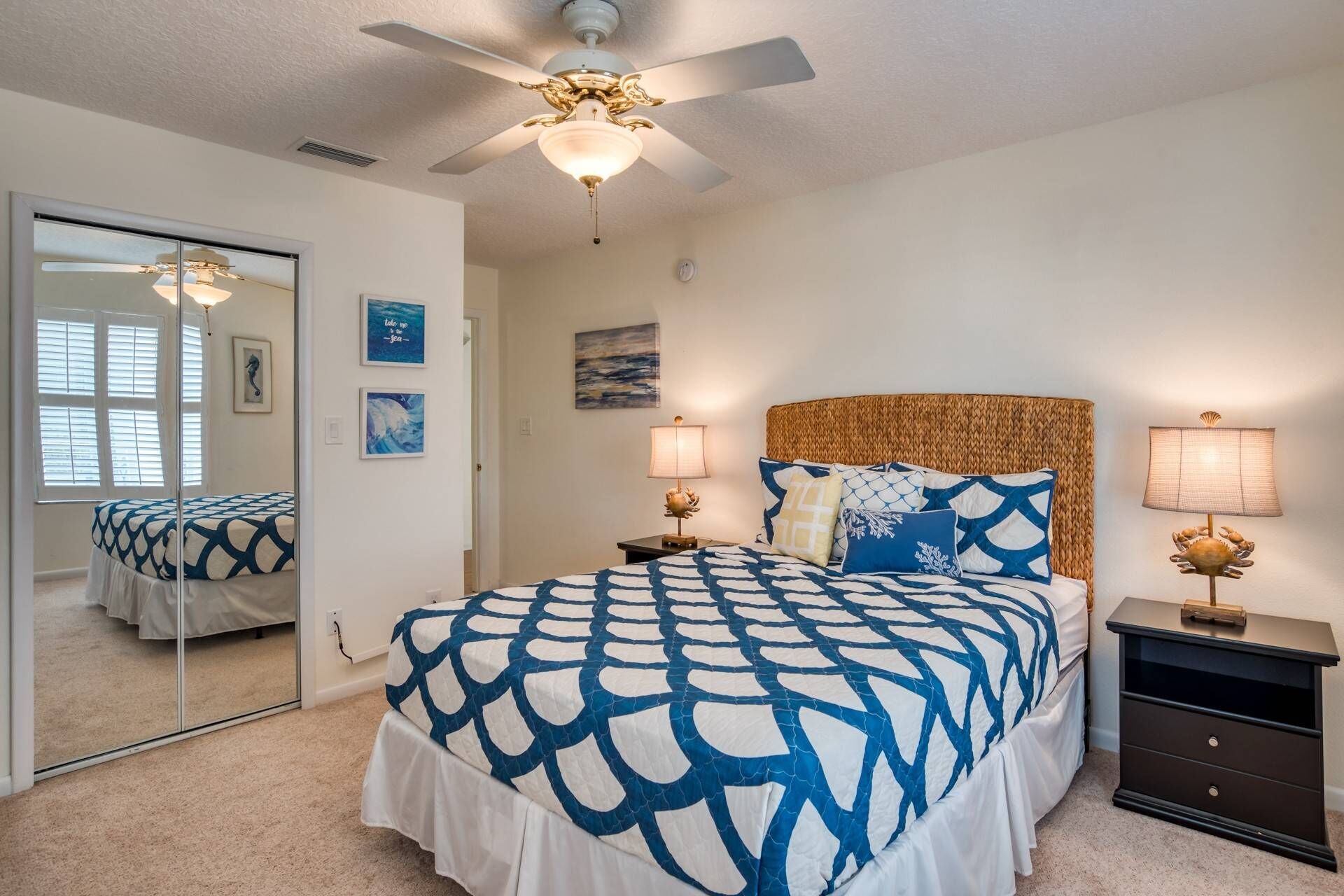 A bedroom with a bed, two bedside tables, a ceiling fan, and a large mirror.