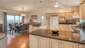 A modern kitchen with a large island, a dining area with a view, and a ceiling fan. - Sunshine Daydream (St. Augustine)