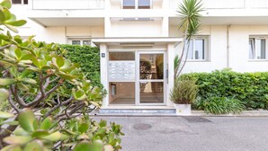 Une entrée d’immeuble avec une porte vitrée, une boîte aux lettres et une petite plante en pot.