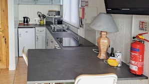A compact kitchen with a sink, a microwave, a kettle, and a fire extinguisher.