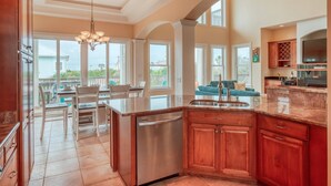 A spacious kitchen with a large island, wooden cabinets, and a built-in dishwasher. - Tuckers Hideaway at Seagate (St. Augustine)